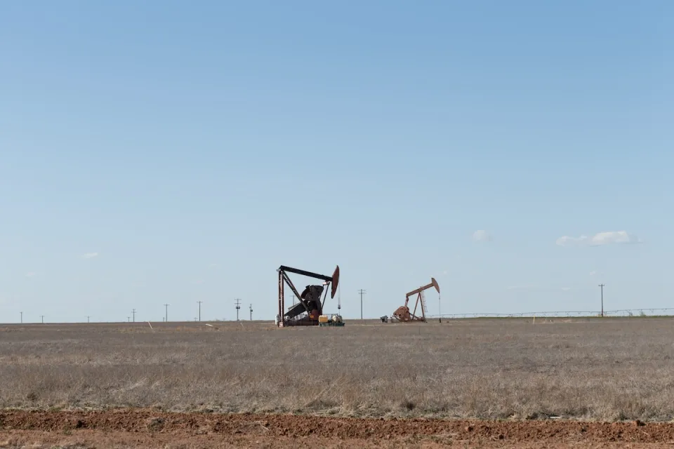 Two oil drilling derricks in vast field in West Texas.